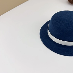 Detail of navy blue wool doll hat with white ribbon trim and elegant academy style finish