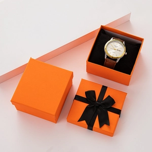 Detail view of orange watch boxes with black bows and soft interior display pillows