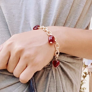 Detailed shot of handmade Murano red heart charms on a thick gold-plated link bracelet