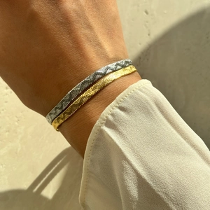 Close-up of gold and silver flat snake chains with textured finish on wrist