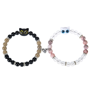 Detail showing heart-shaped magnetic clasp connecting black and white cat beaded bracelets