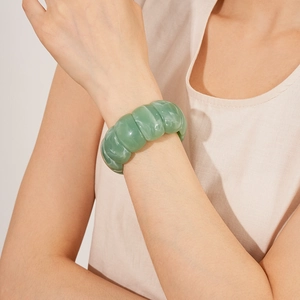 Close-up of a wide green acrylic cuff bracelet with marble texture worn by a model