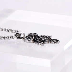 Detailed macro view of vintage silver owl pendant with black stone eyes and intricate texture