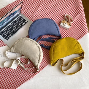 Detailed view of nylon dumpling crossbody bags in blue, beige, and yellow on a checkered cloth