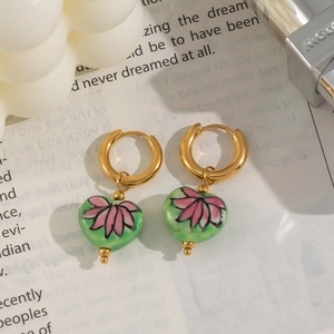 Vue détaillée des boucles d'oreilles créoles cœur avec motif de fleur de lotus rose et vert