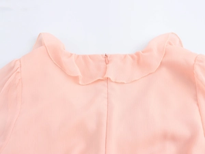 Detail of pink chiffon dress neckline with ruffle trim and hidden zipper on the back