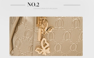 Close-up of golden embossed O-grain leather handbag with elegant butterfly metal charm