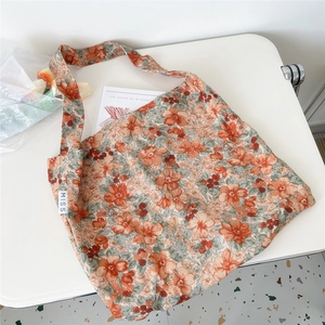 Detailed macro view of orange floral corduroy tote bag with small white MISS woven label