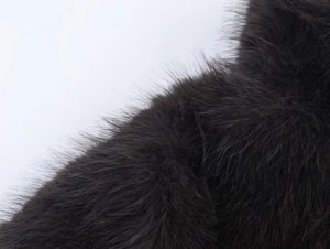 Macro shot of thick black faux fur fabric showing smooth and glossy texture detail