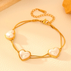 Detail of golden double-layer heart pearl bracelet with delicate snake chain extensions