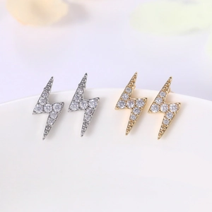 Close-up of gold and silver lightning bolt stud earrings with cubic zirconia stones