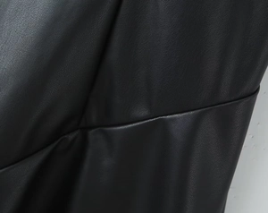 Detalle de la textura de cuero sintético negro con pliegues elegantes y brillo