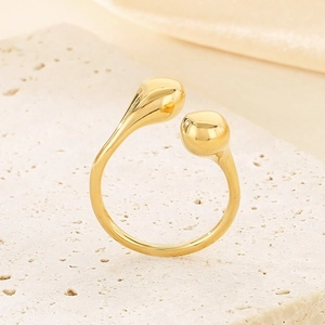Detailed view of gold-plated teardrop and bead ends on a polished open stainless steel ring