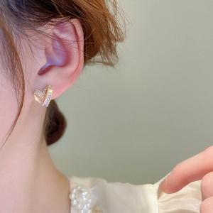 Elegant gold-plated V-shaped zircon stud earrings worn by a model in a close-up shot
