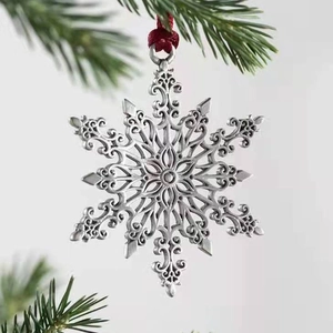 Detailed view of a silver snowflake Christmas ornament hanging on a green pine branch