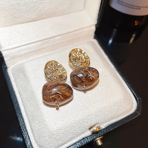 Macro view of vintage gold and amber resin heart earrings with marble texture detail