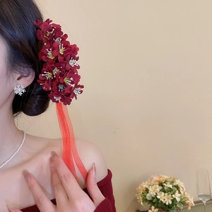 Close-up of wine red fabric flower hairpin with long translucent ribbons and tassels
