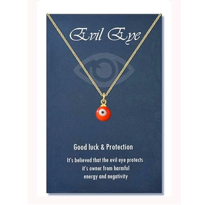 Detail of red evil eye charm on golden chain with dark blue symbolic gift card
