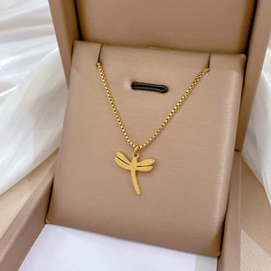 Collana minimalista con ciondolo a libellula dorata su scatola regalo e seta bianca