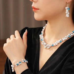 Set gioielli vintage con perle blu e bianche su modella con abito di velluto nero