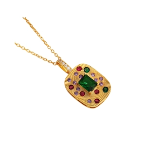 Collana vintage dorata con pendente smeraldo quadrato e cristalli colorati su sfondo bianco