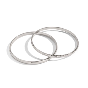 Dettaglio di bracciali in acciaio argento con texture lisce e martellate lucide