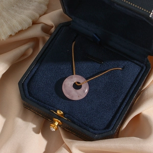 Pink quartz round pendant necklace in a blue jewelry box on beige silk fabric