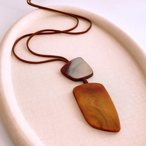 Detail of irregular horn-style pendants in dark brown and amber on a soft cord
