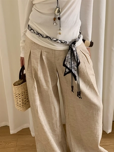 Gros plan d'un pantalon large en lin beige avec taille haute plissée et texture naturelle