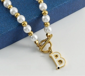 Détail du fermoir à bascule en or 18K et du collier de perles avec pendentif B en nacre
