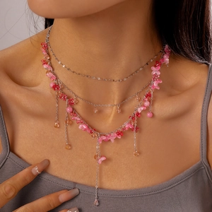 Detail of layered floral necklace with pink resin flowers and long tassel pendants