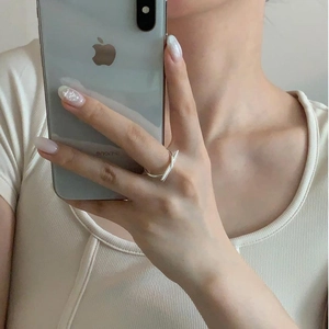 Close-up of a minimalist silver knotted ring worn on index finger in a lifestyle shot