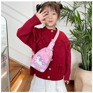 Pink kids crossbody bag with unicorn print worn by a girl near stairs and plants