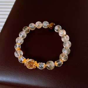 Macro shot of yellow citrine and tiger eye stone beads with golden floral metal spacers