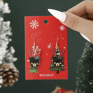 Close-up of reindeer Christmas earrings on a holiday themed card with festive background