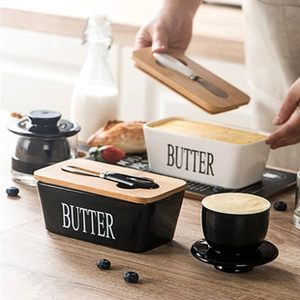 Ceramic butter dishes in black and white with wooden lids and integrated butter knives
