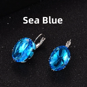 Macro shot of oval aquamarine blue zircon earrings with silver lever-back clasps