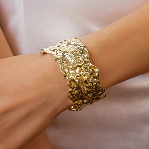Close-up of golden irregular wrinkled texture open bangle on a model's wrist