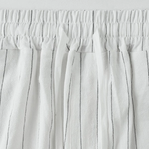 Dettaglio dell'elastico in vita e della coulisse sui pantaloni in lino a righe bianche