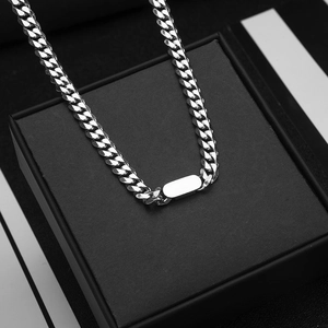 Macro shot of silver titanium steel cuboid pendant on Cuban link chain over jewelry box