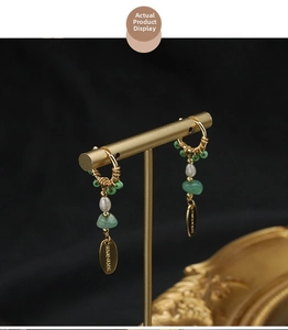 Detail of long handmade pearl earrings with green beads on a golden stand