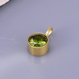 Detail of a round emerald green birthstone pendant with gold plated stainless steel frame