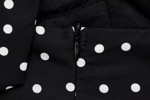 Detailed view of the invisible zipper closure on the black polka dot halter top