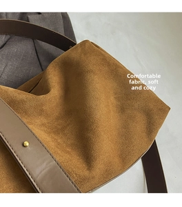 Close-up of caramel suede texture and leather strap with gold studs on handbag