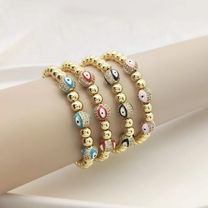 Detailed close-up of 18K gold beaded bracelets with evil eye charms in multiple colors