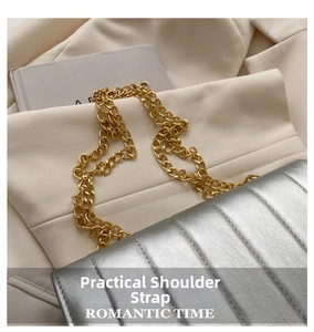 Close-up of a silver quilted shoulder bag with vertical stitching and chunky gold chain