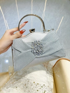 Macro detail of silver pleated evening bag featuring a crystal flower and metal handle