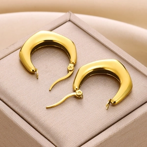 Macro shot of 18K gold geometric earrings resting on a luxury jewelry box texture
