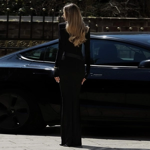Détail d'une robe longue noire ajustée avec un dos nu élégant et des manches longues