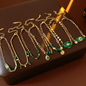 Détail de bracelets chaîne en acier vintage avec pendentifs malachite verte et fini doré